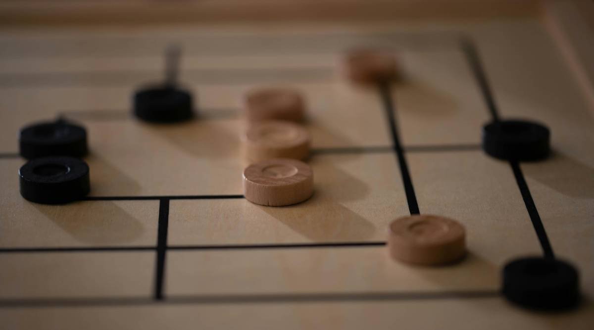 An in-game scene with light and dark wooden pieces strategically placed on a board, captured with a shallow depth of field.