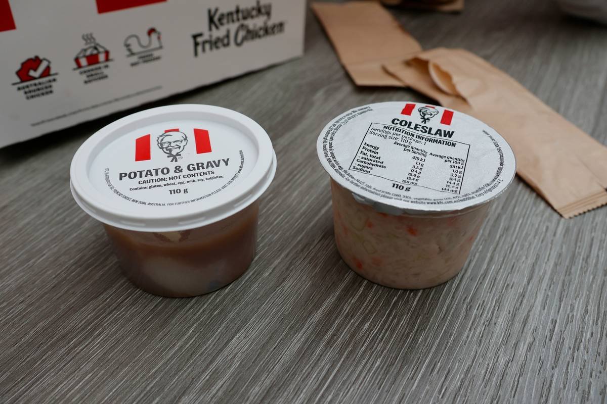 Two kfc containers of potato and gravy and coleslaw.